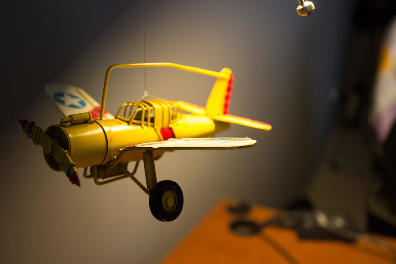 Close-up of a vivid yellow model airplane hanging indoors, capturing motion and detail.