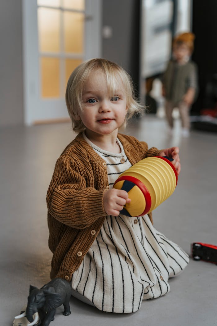 Cute toddler with blonde hair playing with a toy indoors. Cozy and stylish atmosphere.